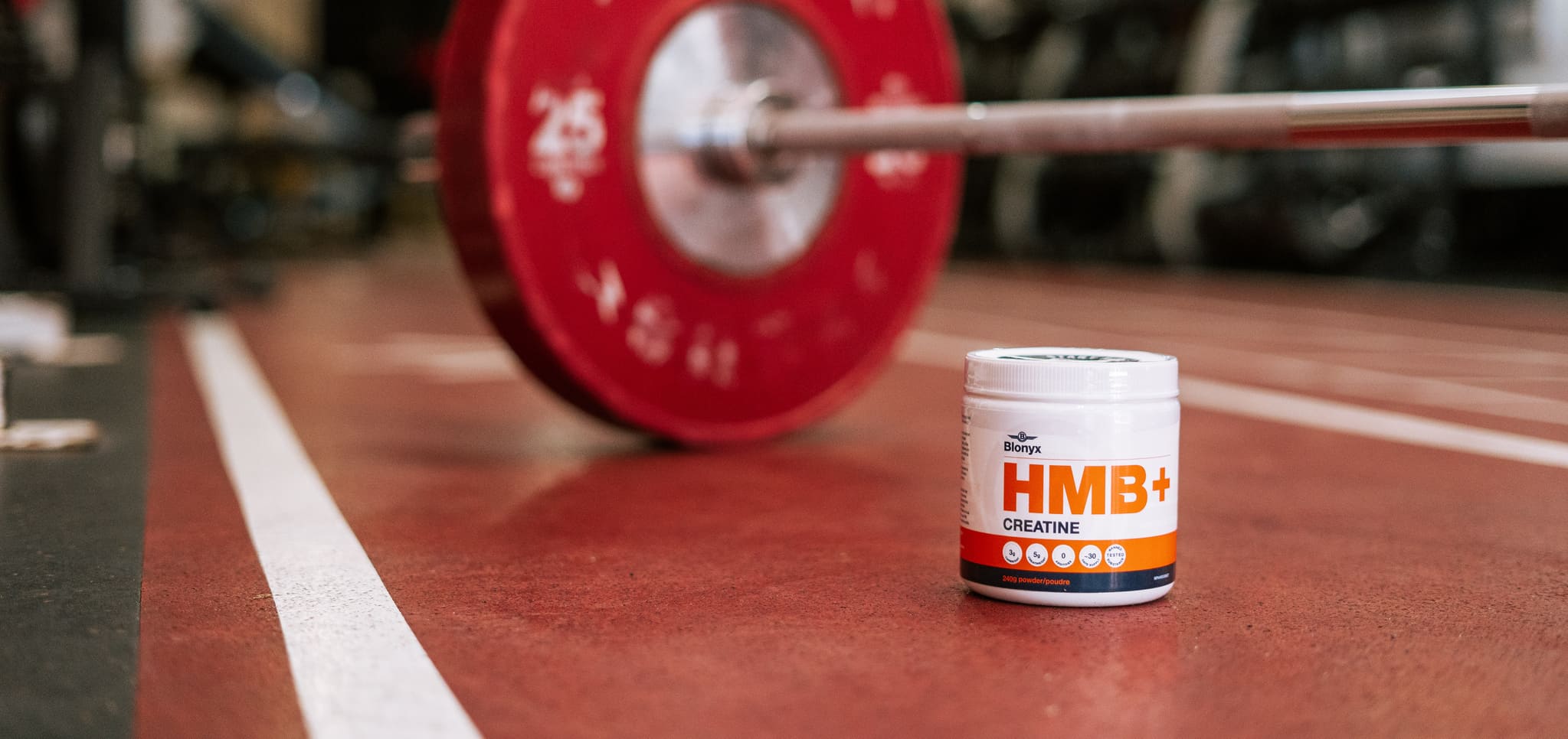 Blonyx HMB+ Creatine In Front of a Bar Bell