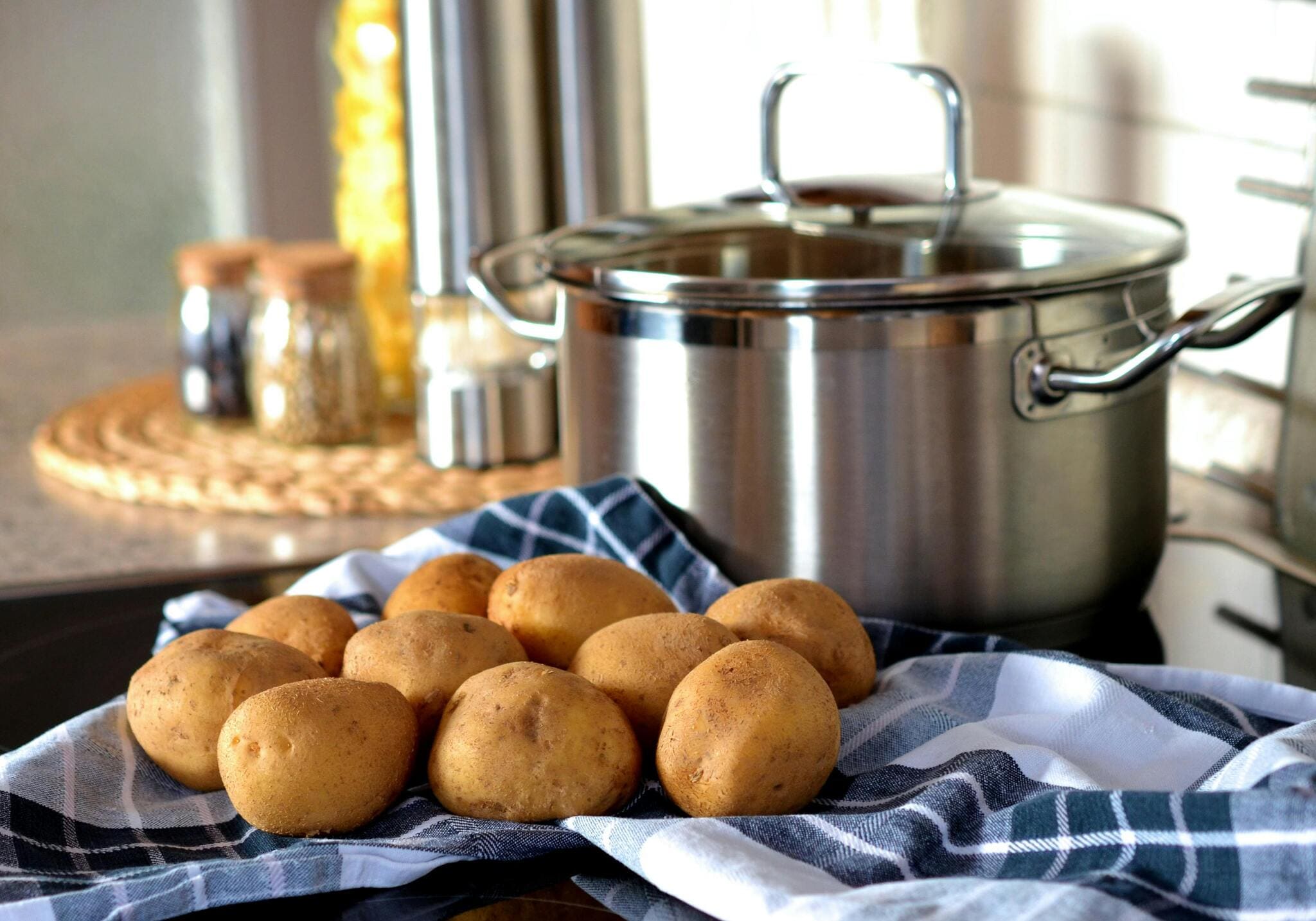 Potatoes beside a steel pot on the stove