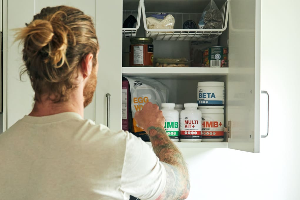 Person reaching into a cabinet filled with Blonyx supplements.