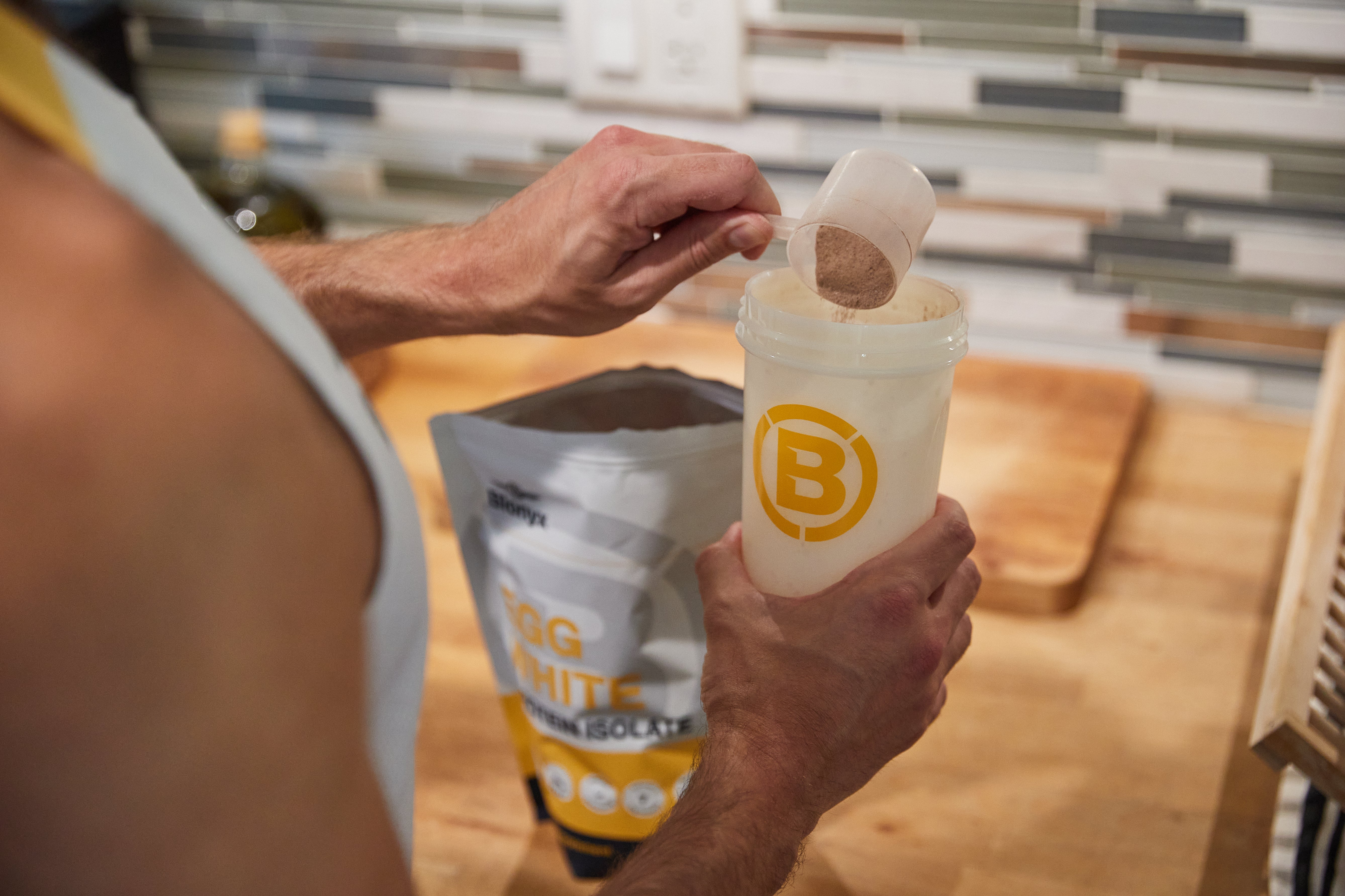 Athlete scooping Blonyx Egg White Protein Isolate into a shaker