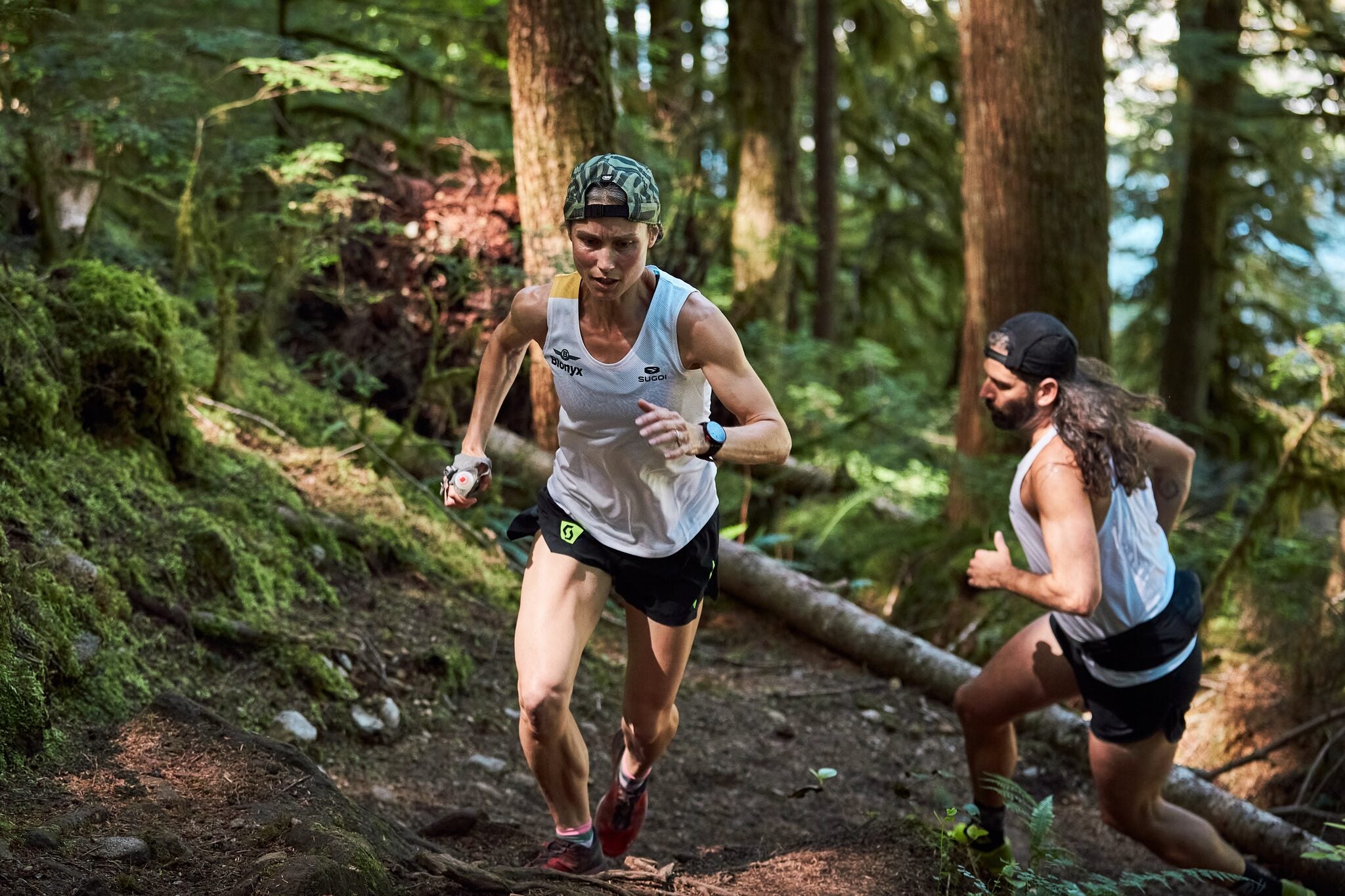 Pair of trail runners climbing a trail in the forest