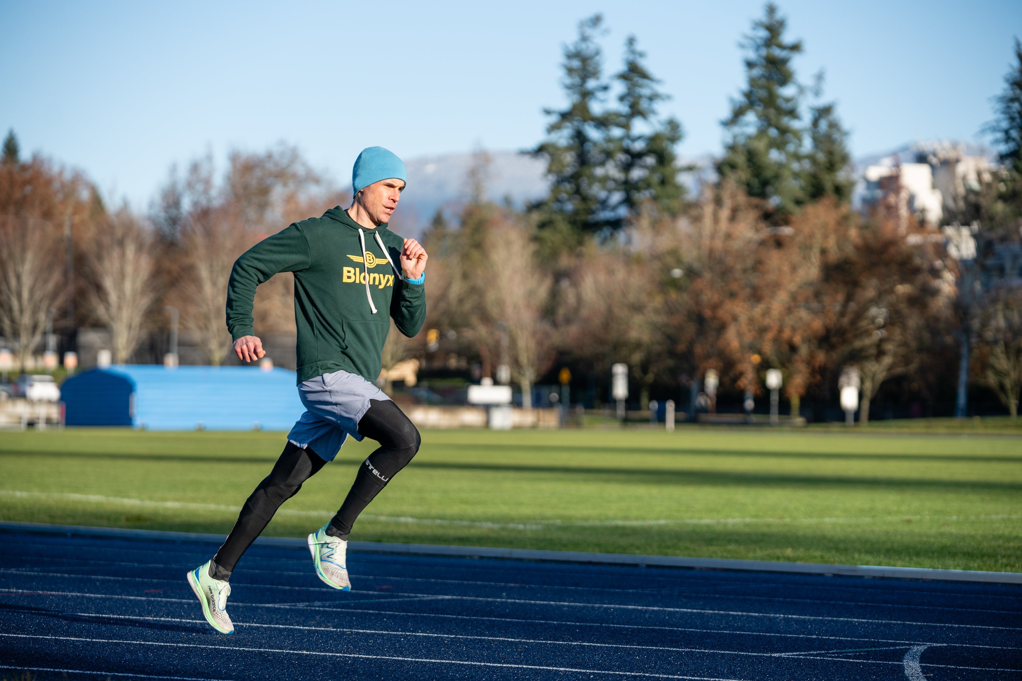 Man sprinting on a track in a Blonyx hoodie
