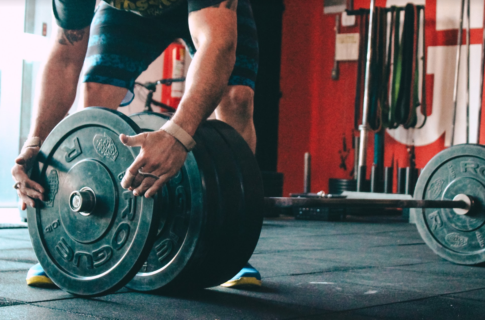 An athlete putting a plate on a bar.