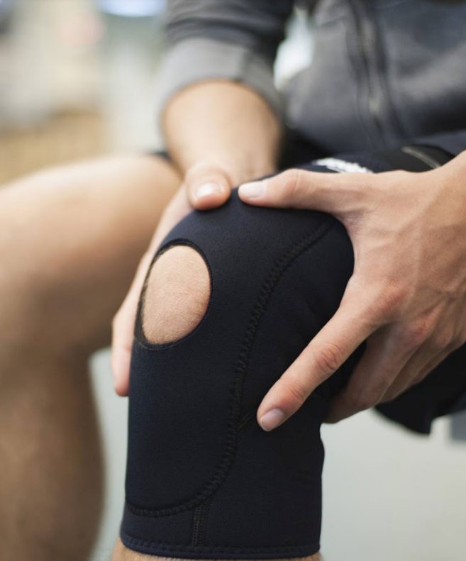 An athlete holding their knee in a brace