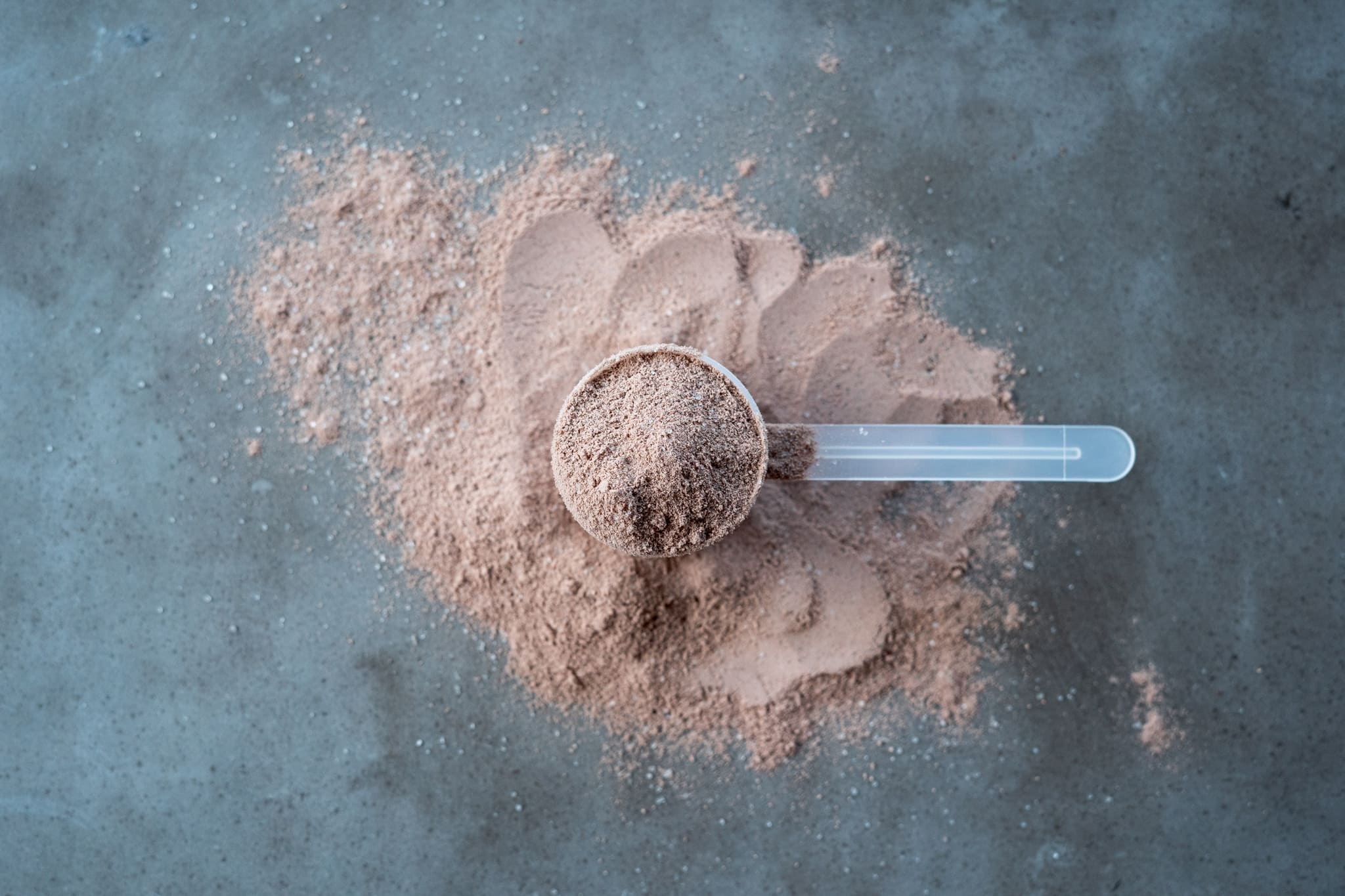 Scoop of Blonyx Egg White Protein Isolate on a concrete table