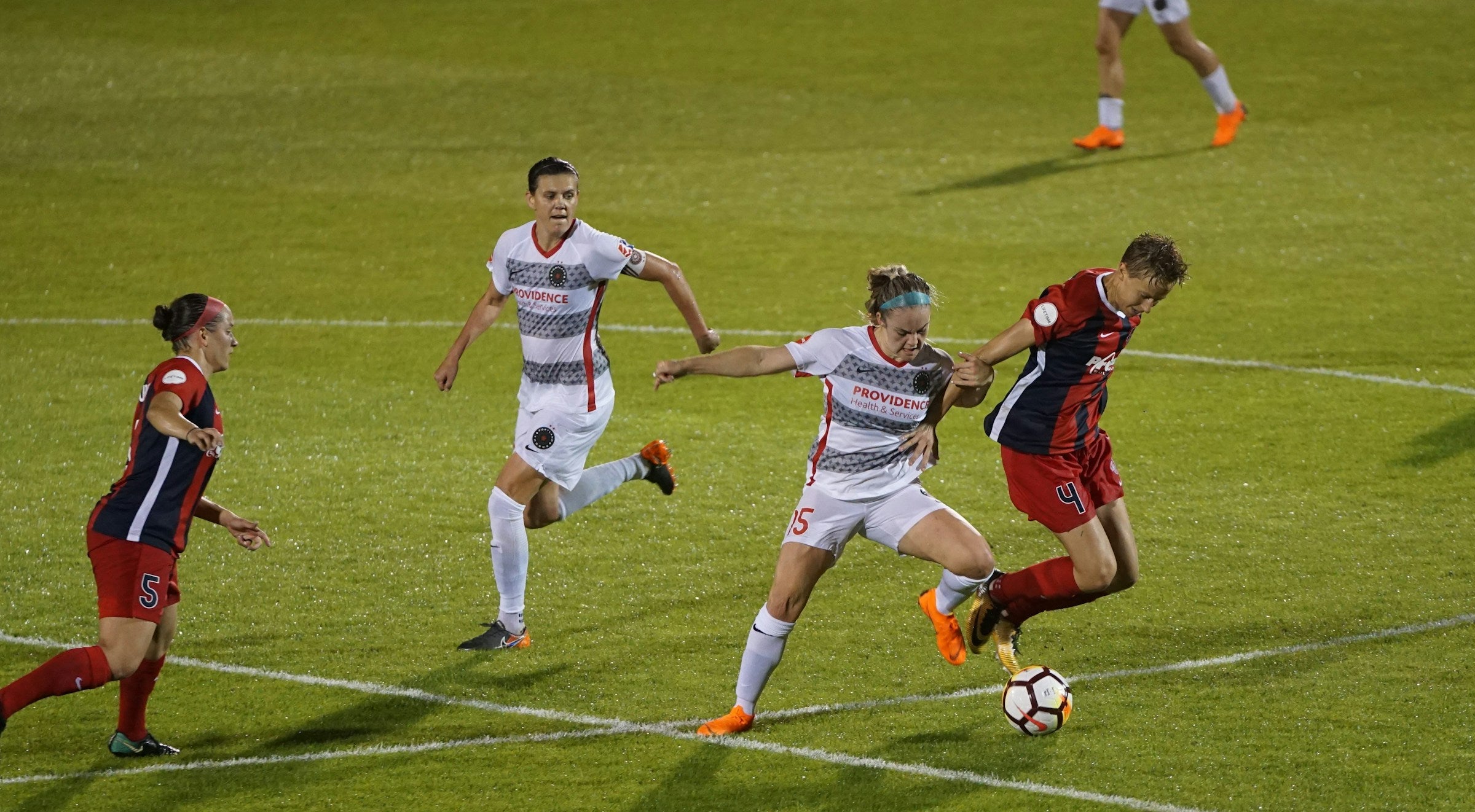 Soccer players running for the ball on the field