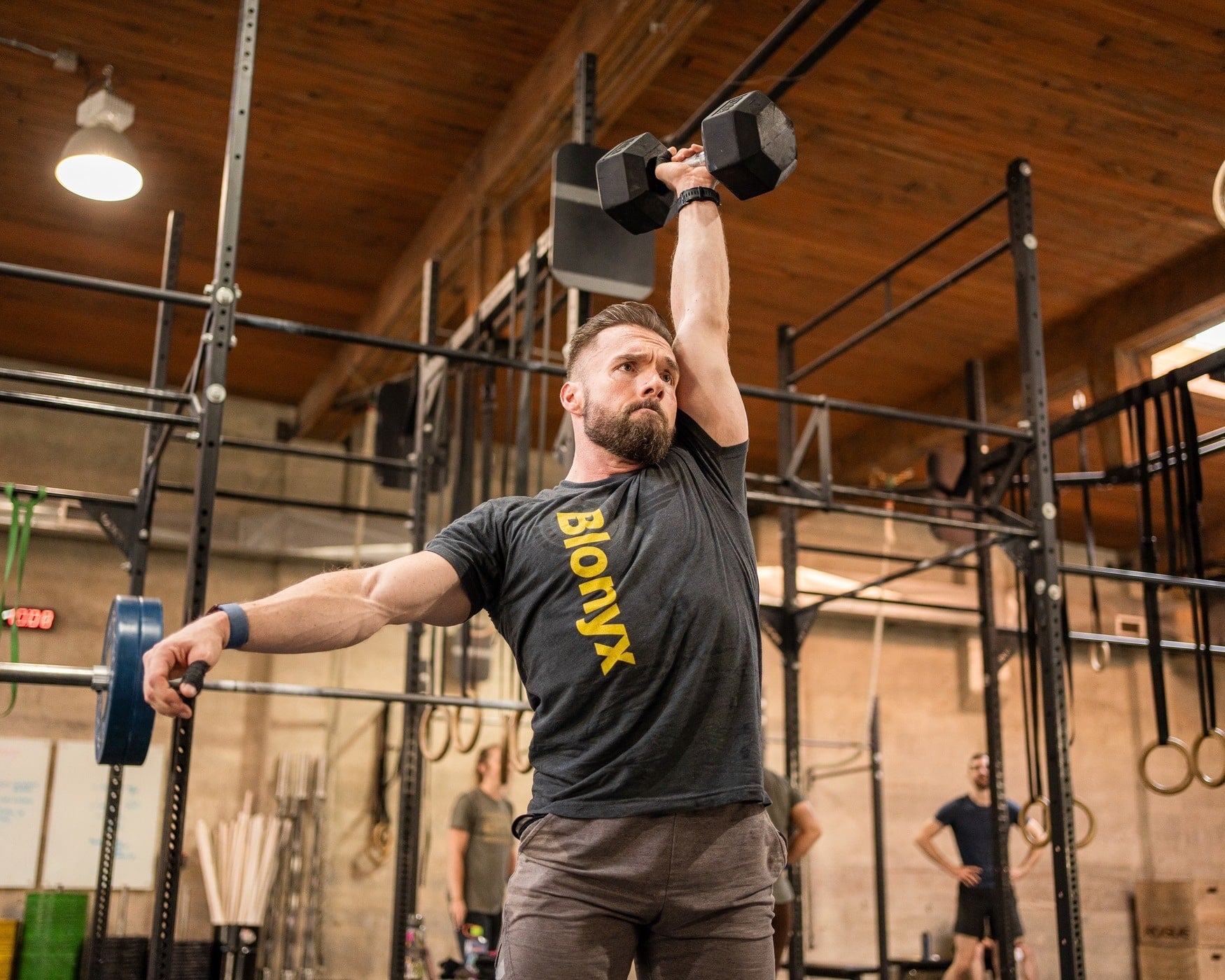 CrossFit athlete throwing a dumbbell over their head