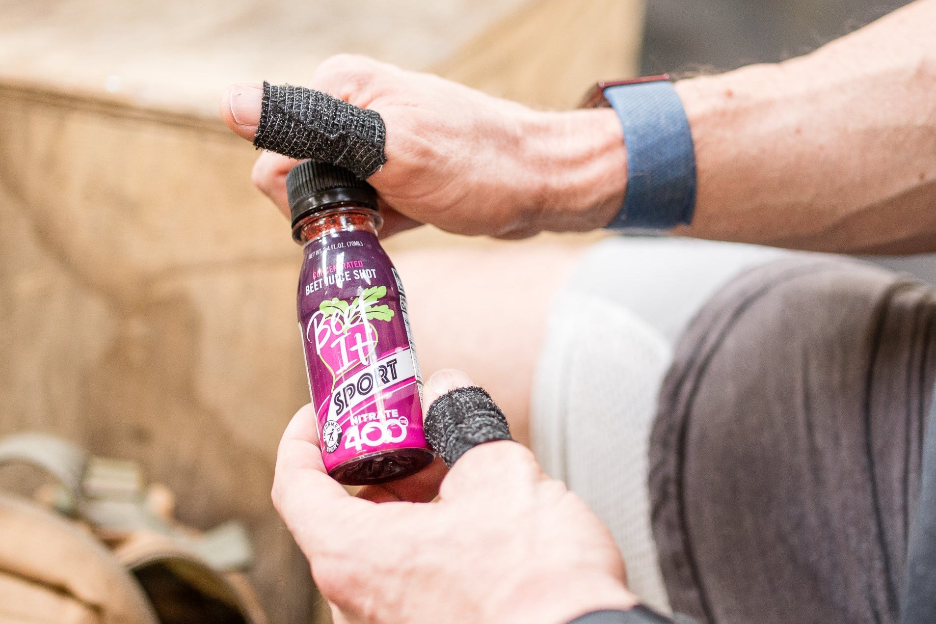Person holding a small bottle with a purple label in a workout setting