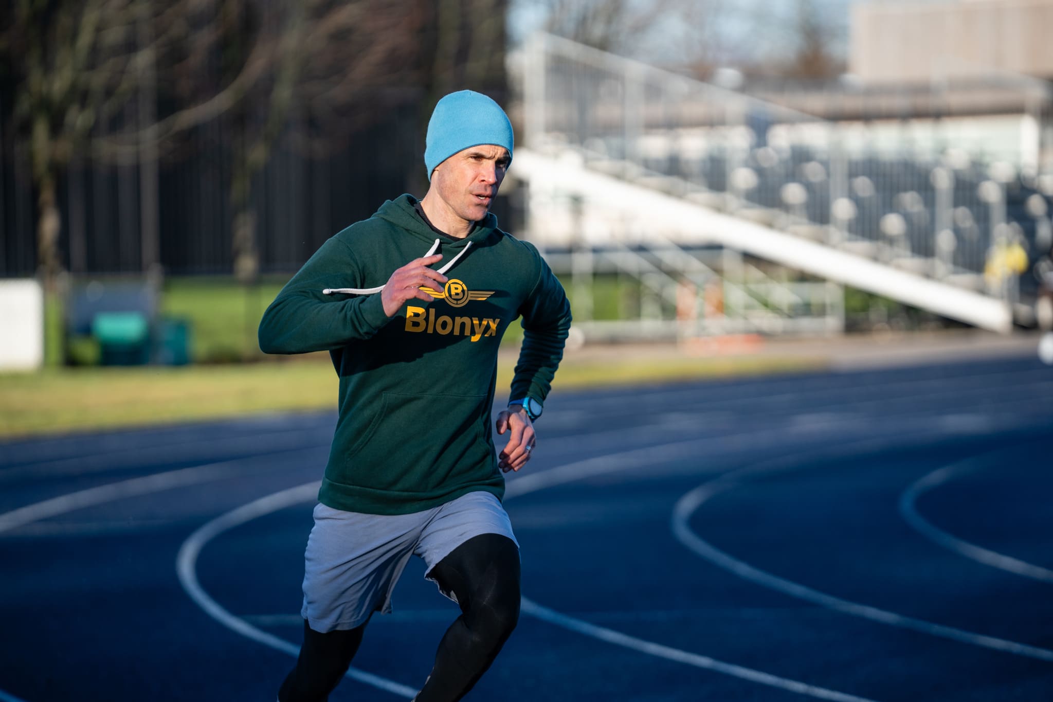 Runner sprinting on a track in a Blonyx hoodie