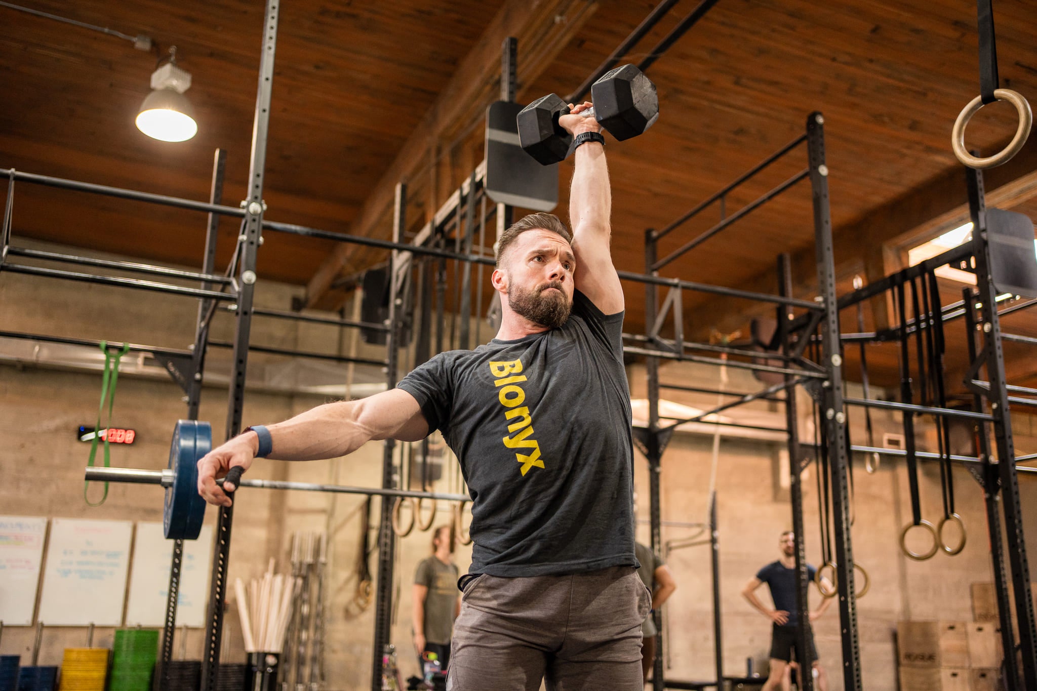 Man lifting weights wearing a Blonyx shirt in a gym setting