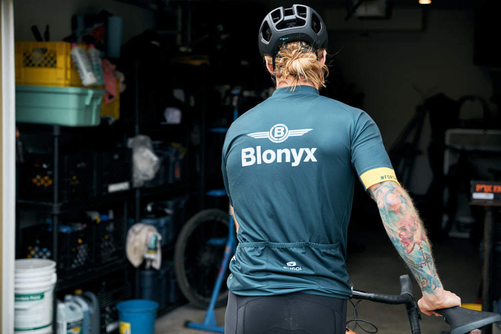 Person wearing a Blonyx shirt in a garage with a bike