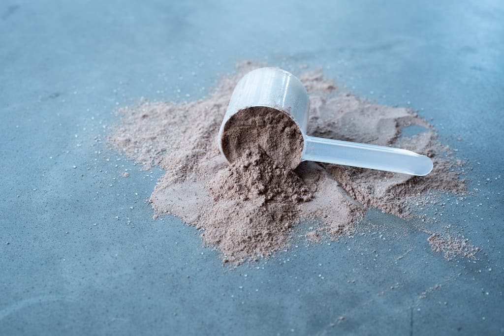 A scoop of Blonyx Egg White Protein Isolate on a concrete table.