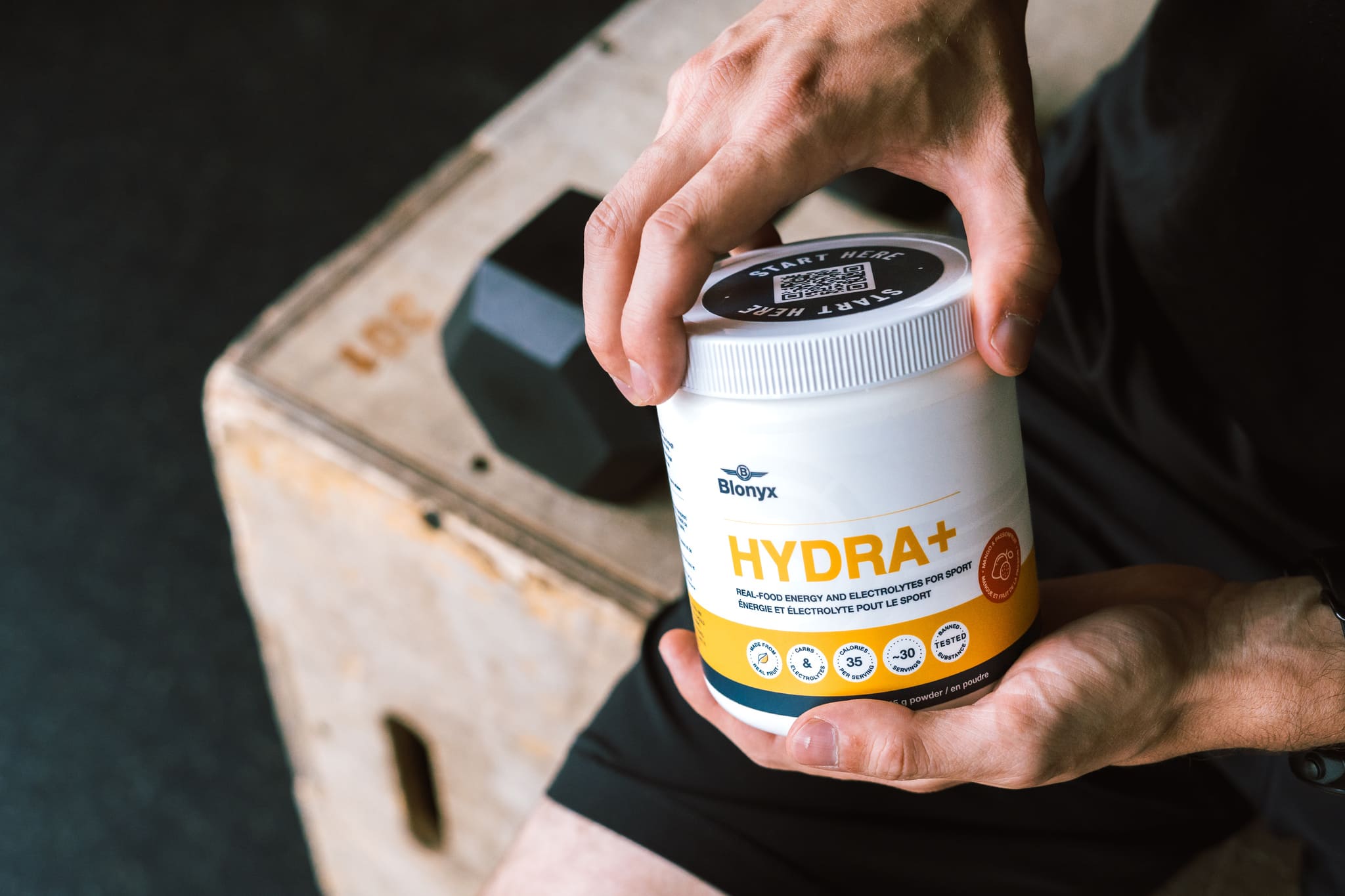 Person holding a container of Blonyx HYDRA in a gym