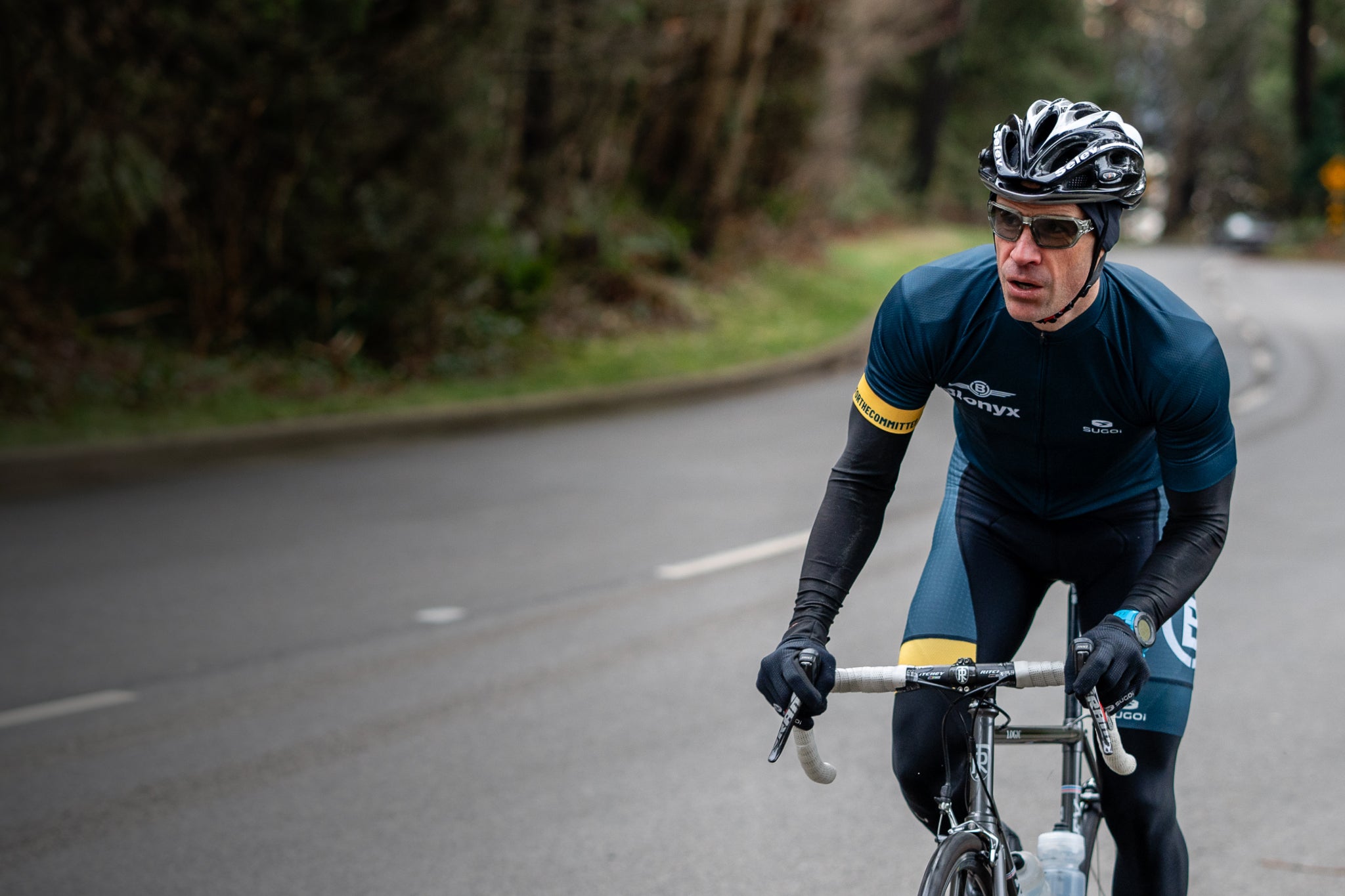 Cyclist in a blue outfit riding on a road with trees in the background