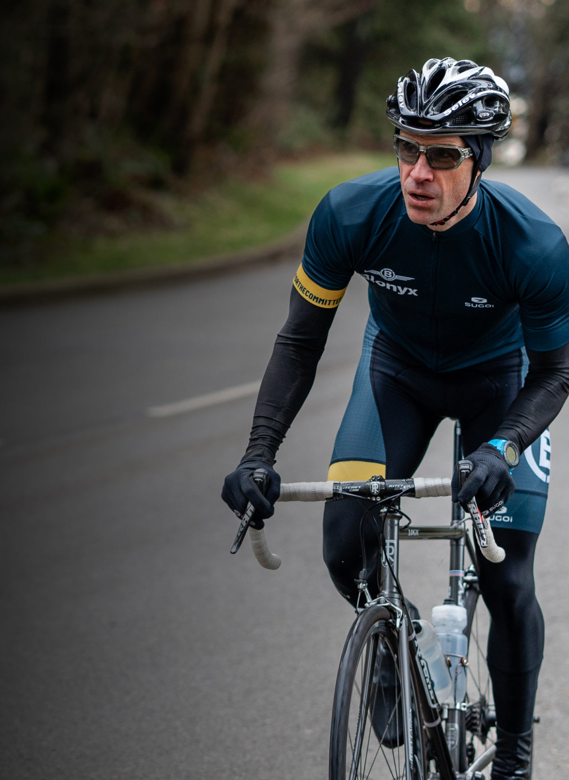 Cyclist in a blue outfit riding on a road with trees in the background
