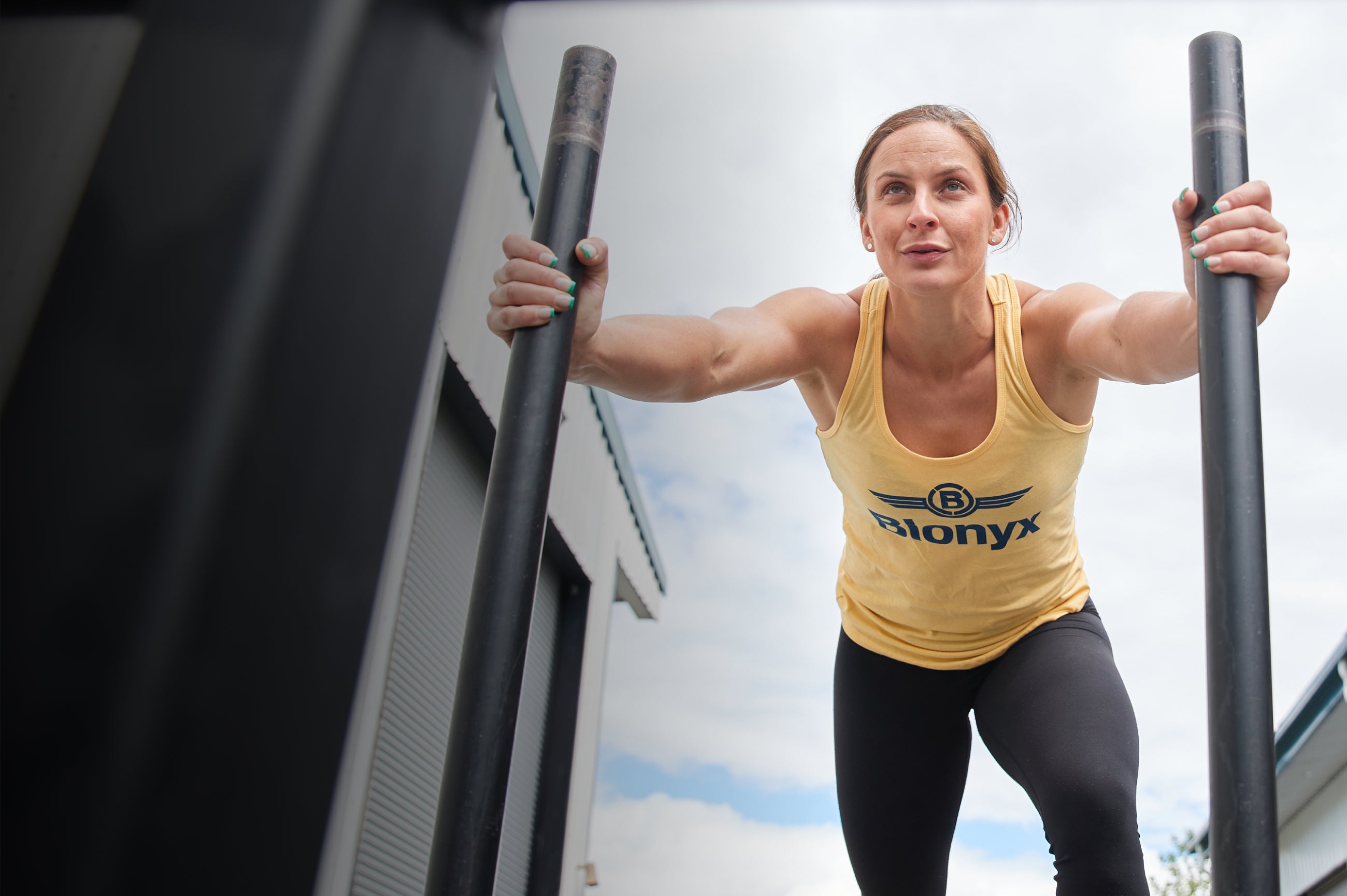 An athlete performing sled pushes in a yellow Blonyx tank top