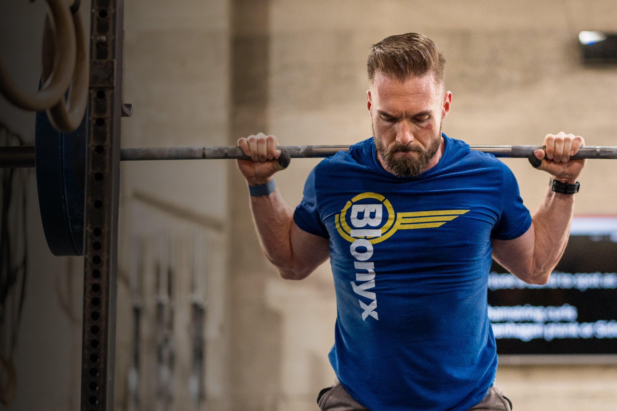 A CrossFit athlete performing squats in a blue Blonyx tee shirt