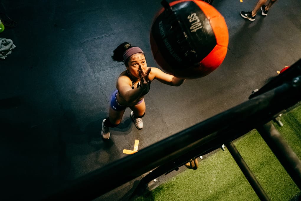 Person performing wallballs with a medicine ball in a gym 