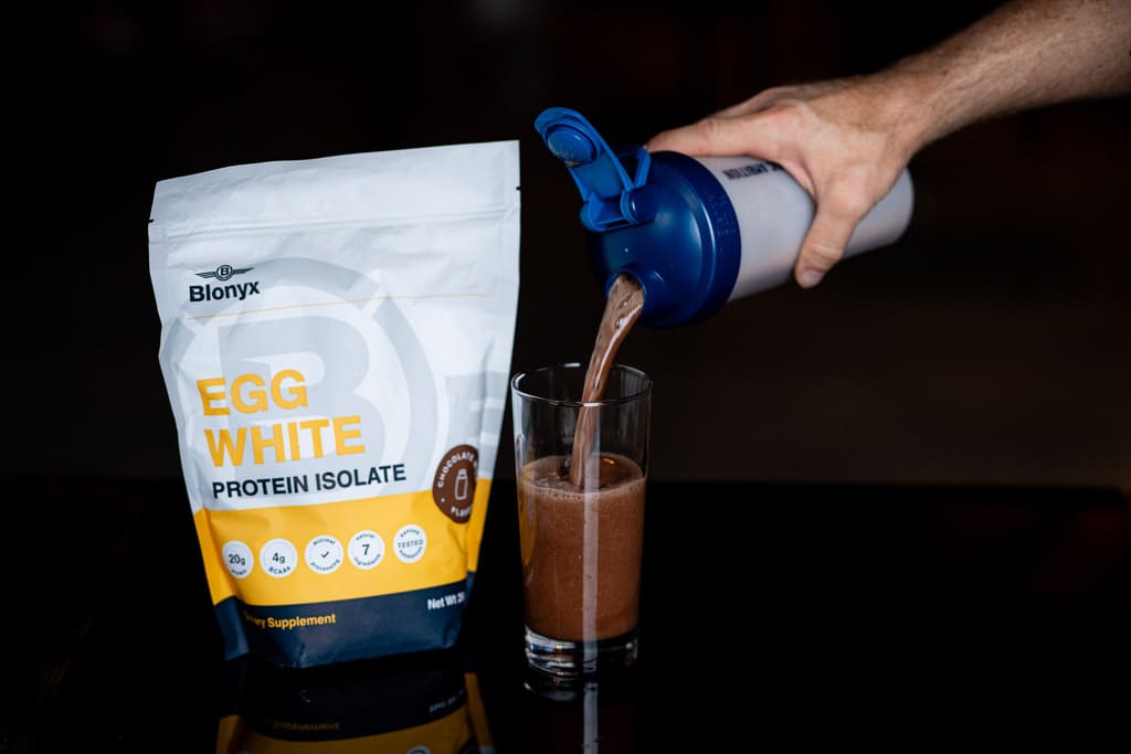 Person pouring Blonyx Egg White Protein Isolate into a Glass