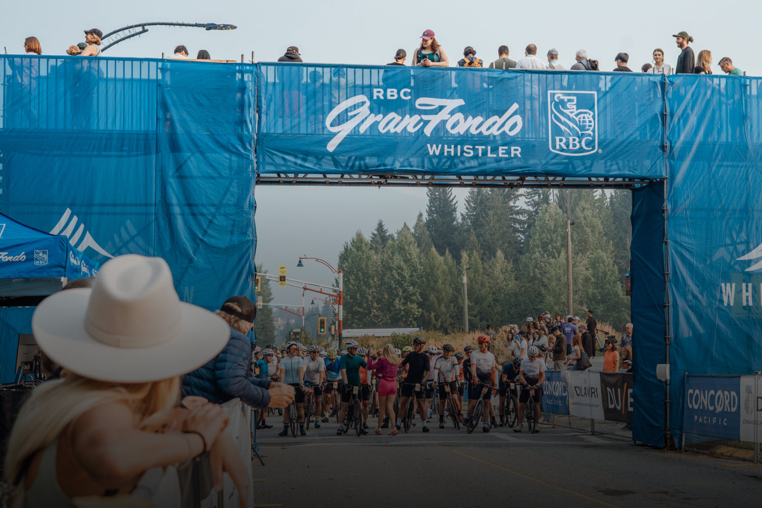 RBC GranFondo Whistler event with participants crossing the finish line under a blue RBC banner.