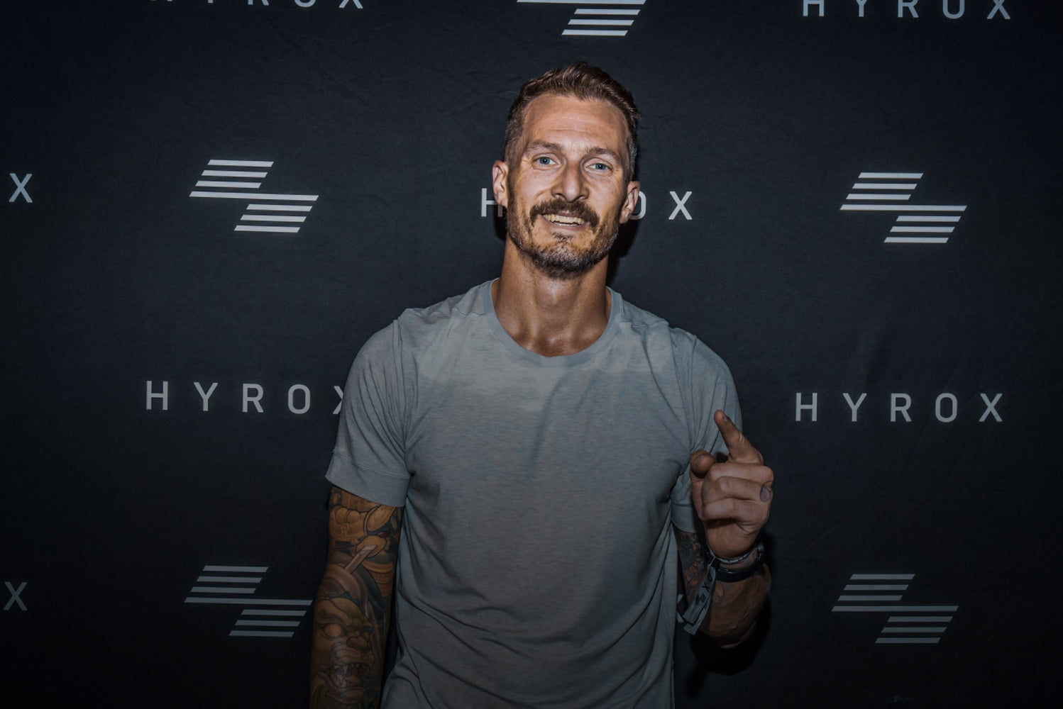 Man posing in front of a black backdrop with 'HYROX' branding