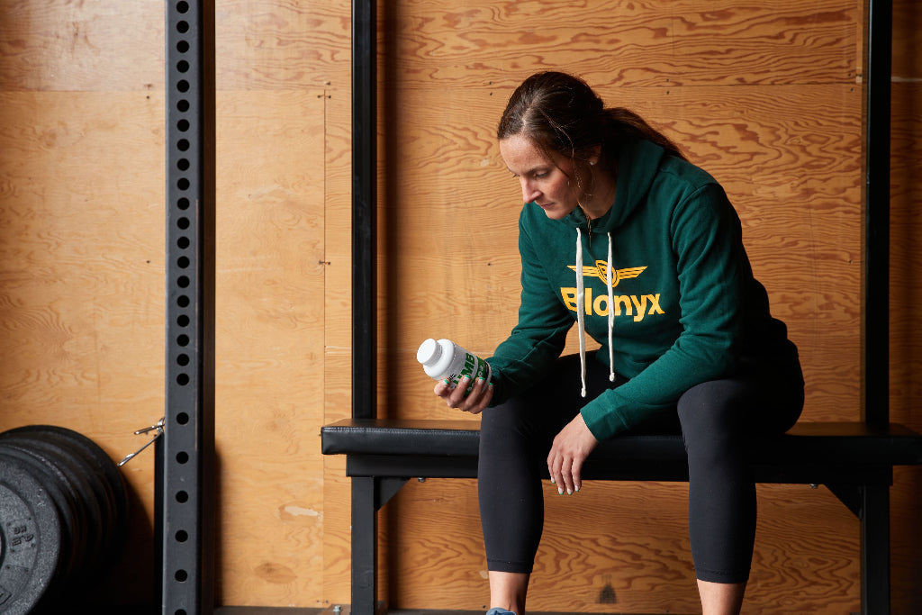 Woman reading the label on a bottle of Blonyx HMB Sport